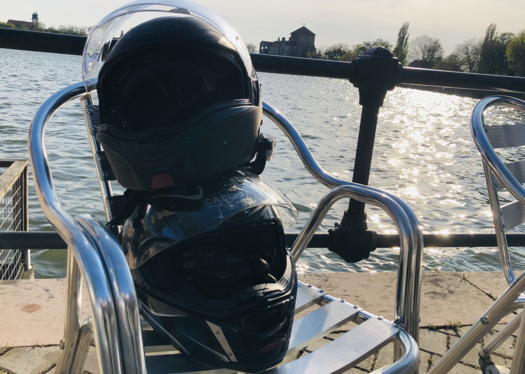 Two helmets stacked on each other on a chair in a terrace overlooking the lake of Tata in Hungary.