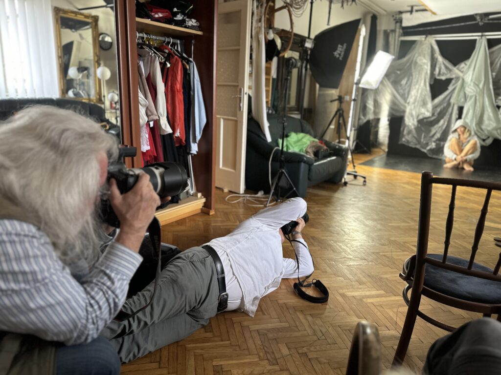 Laci Fábián is on the floor and Szilárd Bordrogközi on his knees trying to capture SophieS in a pose while she is sitting curled up on the floor.