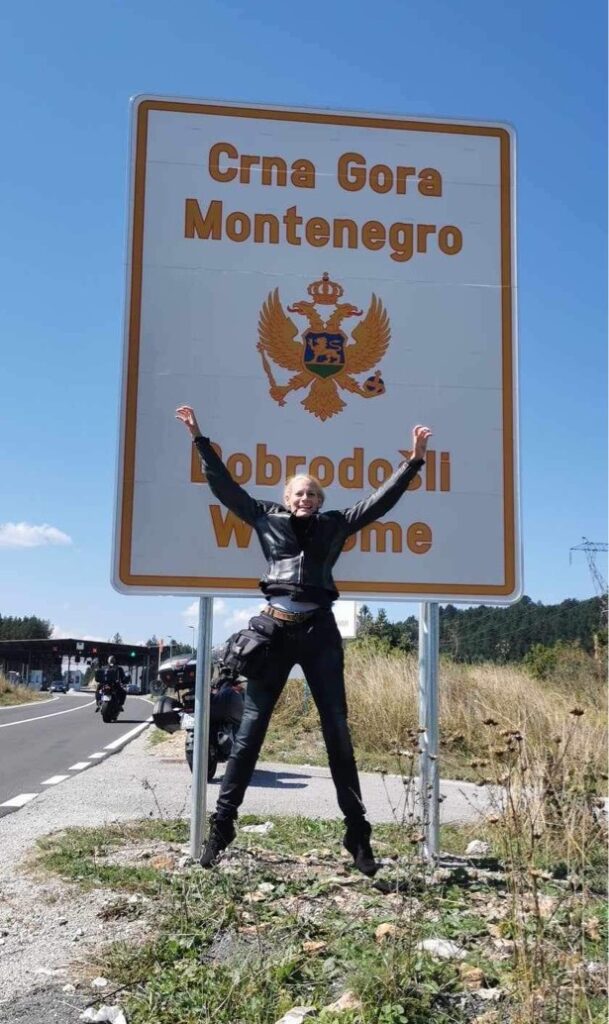 Sophies starfish jump in front of a Welcome to Montenegro sign at the border.