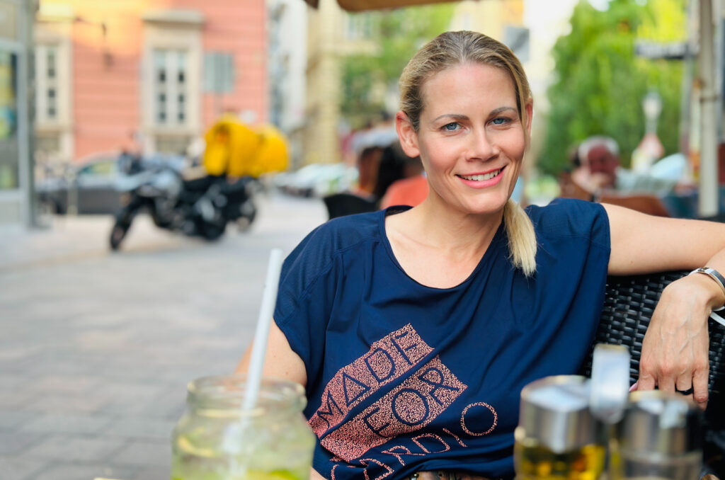 Sophie sitting in an outdoor coffeehouse, enjoying a drink after getting off the motorbike.