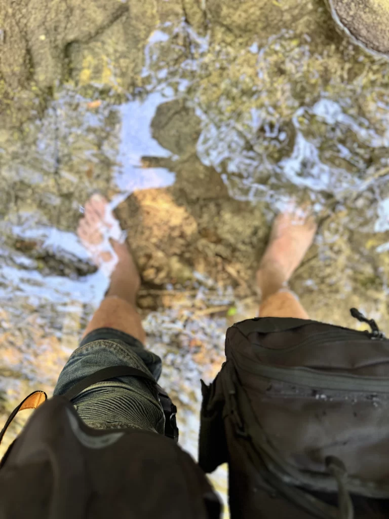 A picture of Rag dipping his feet in a beautiful stream near Ochiul Beiului in Romania