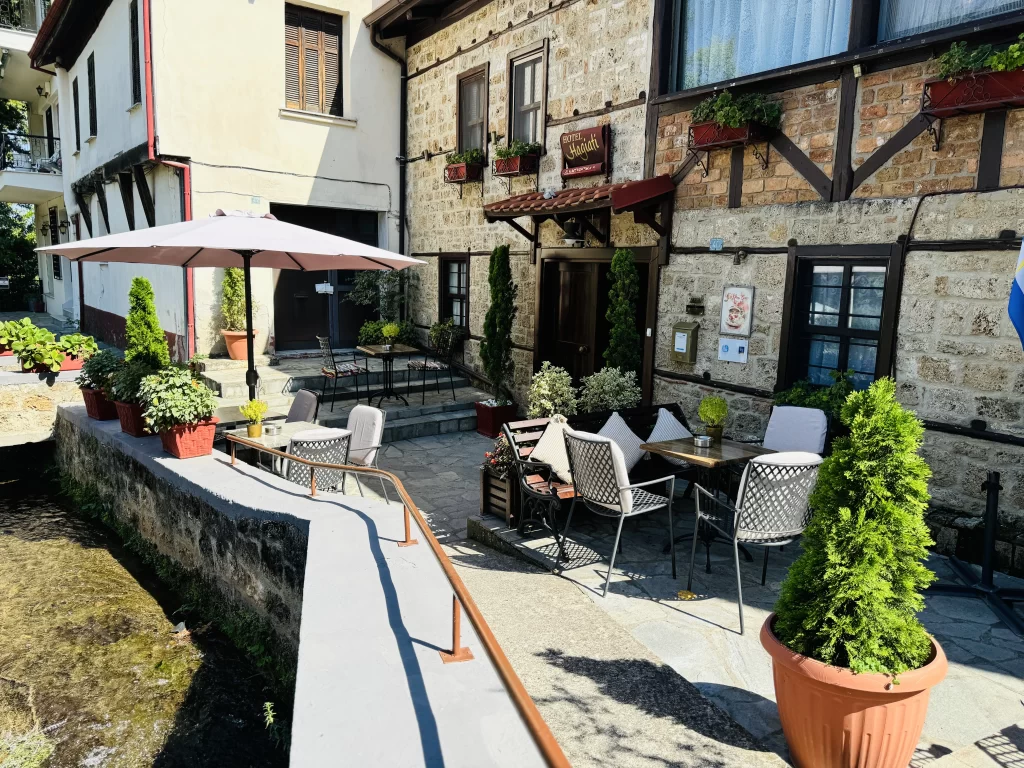 Edessa hotel from the outside, showing the rustic front and the stream in front of it.