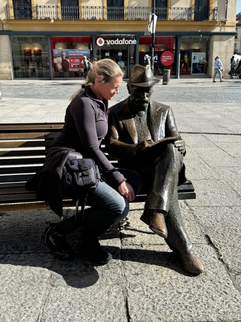 Zsófi a téren egy padon ülő szoborral pózol.
