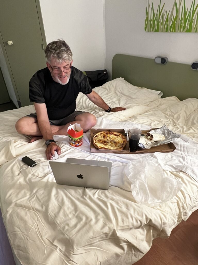 Ken ül az ágyon egy nagy doboz kebabbal az ölében: hotelvacsora egyszerűen.